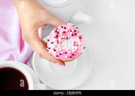 Köstlicher Donut in weiblicher Hand, Draufsicht Stockfoto