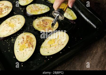 Weibliche Hand Gießen Öl über Auberginen Scheiben Stockfoto