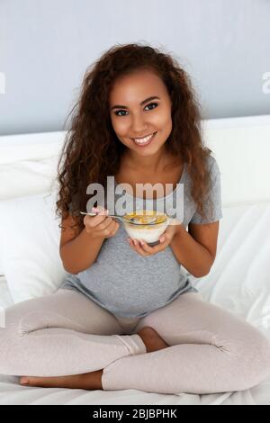 Attraktive schwangere afrikanische Frau essen Getreide Stockfoto