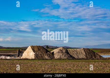 Salzhaufen und wunderschöne bunte Landschaft an den Salzpfannen in der Nähe von Porto Lagos Fischerdorf in Nordgriechenland. Einige Maschinen. Sonniger Spätherbst Stockfoto