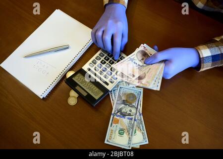 Hand in Handschuh Schulden auf Rechner vor dem Hintergrund des Geldes Stockfoto