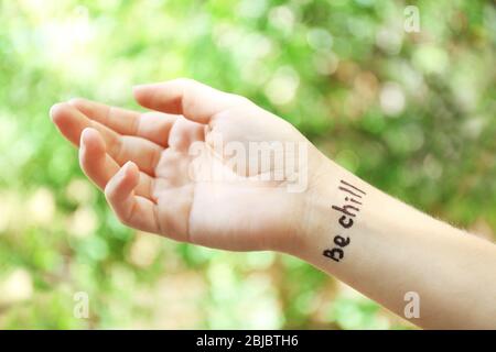 Weibliche Hand mit Tattoo Wort CHILL, Outdoor Stockfoto