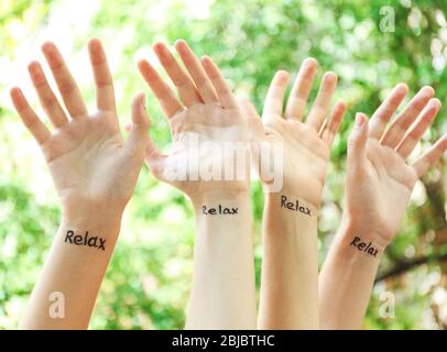 Weibliche Hände mit Tattoo Wort ENTSPANNEN, im Freien Stockfoto