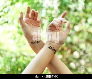 Weibliche Hände mit Tattoo Wort ENTSPANNEN, im Freien Stockfoto