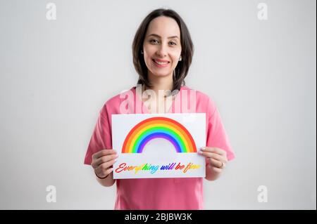 Junge Frau medizinische Fachkrankenschwester oder Ärztin mit rosafarbener Krankenhauskleidung, mit braunem Haar, mit einem weißen Papier und einem Smiling, das auf einem w posiert Stockfoto