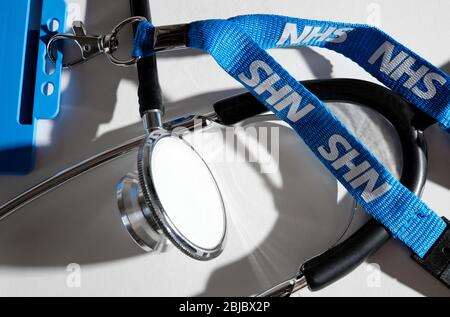 Arztstethoskop und nhs-Trageschlaufe auf weißem Hintergrund Stockfoto