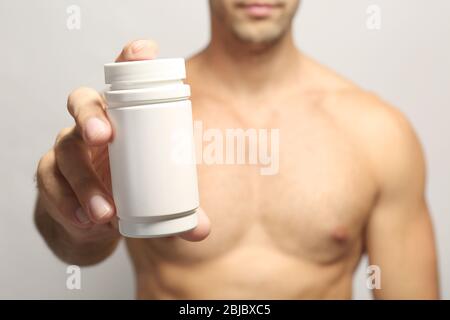 Muskulöse Mann hält Drogen in der Flasche, Nahaufnahme Stockfoto