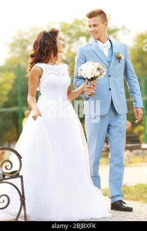 Wunderschönes Hochzeitspaar, das im Park spazieren geht Stockfoto