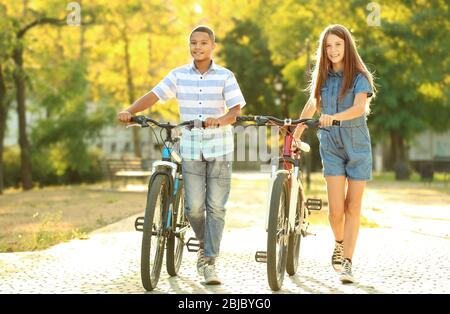 Freunde mit Fahrrädern, die an sonnigen Tagen im Park spazieren Stockfoto