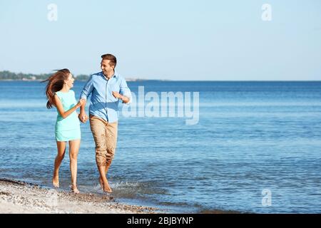 Glückliches Paar, das verliebt ist, am Strand entlang zu laufen Stockfoto