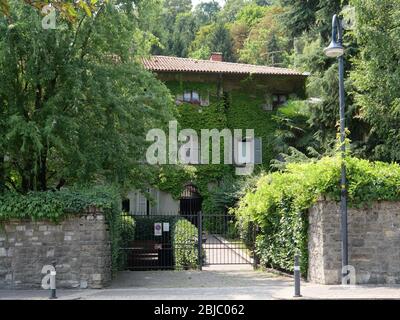 Großes schönes Vintage-Haus mit grünem Efeu bedeckt und umgeben von üppigen grünen Garten Stockfoto