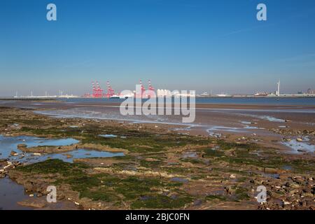 Stadt Wallasey, England. New Brighton Beach mit dem Fluss Mersey und den roten Kränen am Seaforth Container Terminal, im Hintergrund. Stockfoto