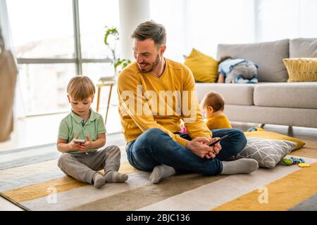 Glücklicher Vater und Sohn spielen auf dem Handy zu Hause