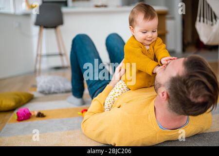 Glücklicher junger Vater spielt mit kleiner Tochter zu Hause Stockfoto