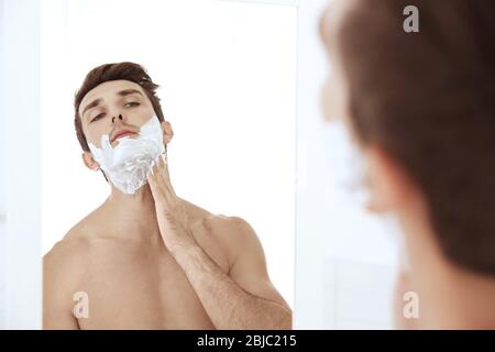 Junger schöner Mann, der sich im Badezimmer sein Gesicht rasieren konnte Stockfoto