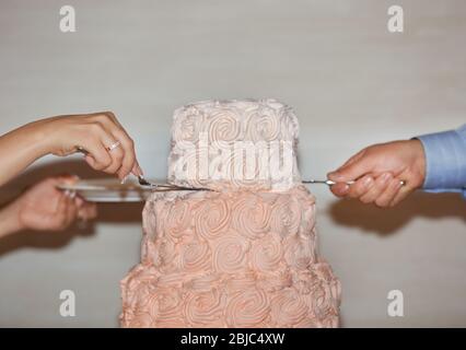 Bräutigam und Braut schneiden Hochzeitstorte im Restaurant Stockfoto