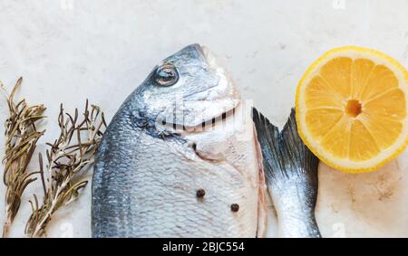 Frischer roher Dorado-Fisch auf einem weißen Tisch mit Kochzutaten. Draufsicht mit einer Kopie des Raums, selektiver Fokus. Stockfoto