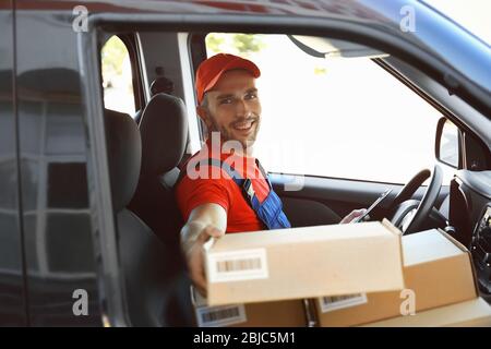 Liefermann mit Paketen im Auto Stockfoto