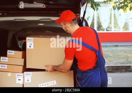 Liefermann Entladen Paket aus dem Auto Stockfoto