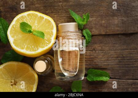 Ätherisches Öl mit Minze und Zitrone auf Holztisch Stockfoto