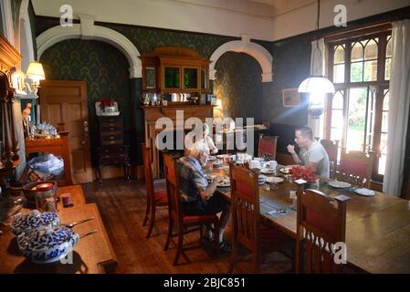 Dreiköpfige Familie mit Frühstück im alten Kolonialstil Sandstein Bauernhaus von Sir Herbert Baker entworfen. Stockfoto