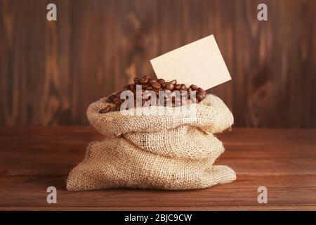 Geldbörse mit gerösteten Kaffeebohnen auf Holzhintergrund Stockfoto