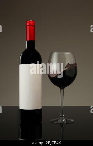 Flasche Rotwein und Glas mit neutralem Hintergrund Stockfoto