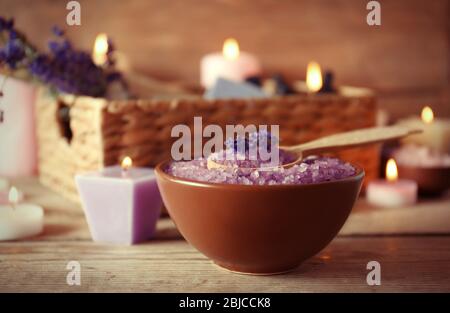 Spa-Konzept. Schüssel mit Lavendel Meersalz und Kerzen auf Holzhintergrund Stockfoto