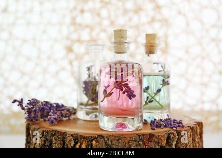Flaschen mit Lavendelöl und Blumen auf Holz auf verschwommenem Hintergrund Stockfoto
