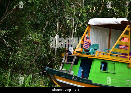 Indonesischer Junge in einem Boot mit einem Schleuder im Dschungel von Kalimantan. Stockfoto