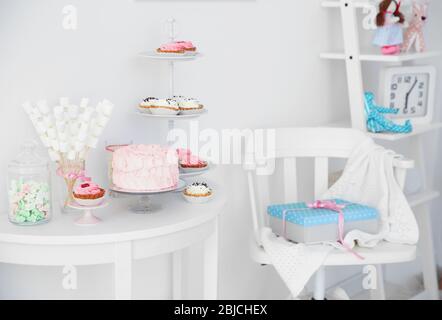 Leckere Süßigkeiten auf dem Tisch im Zimmer für Geburtstagsfeier dekoriert Stockfoto