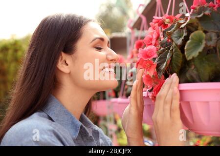 Hübsche junge Frau mit Begonia Blumen, Nahaufnahme Stockfoto