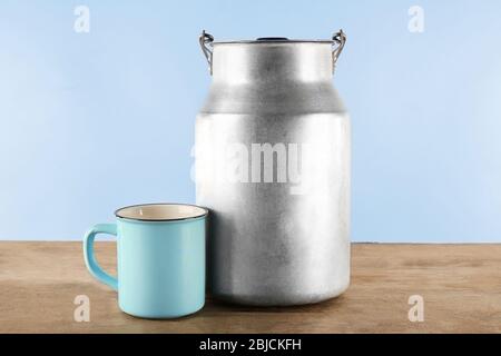 Aluminium Milchbehälter mit Tasse auf Holztisch Stockfoto