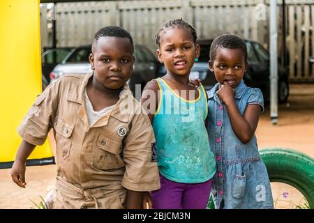 Johannesburg, Südafrika - 7. Dezember 2016: Drei junge afrikanische Kinder zeigen Freundschaft und Freude in einer Soweto Township Stockfoto