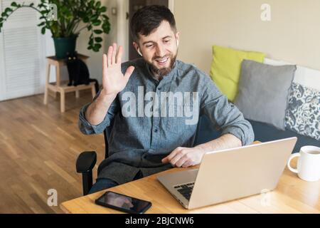 Ein schöner osteuropäischer Mann, der während der Quarantänesperre des Corona-Virus von zu Hause aus arbeitet und online mit seinen Kollegen chatte Stockfoto