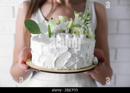 Frau mit Kuchen dekoriert mit Marshmallows und Blumen Stockfoto