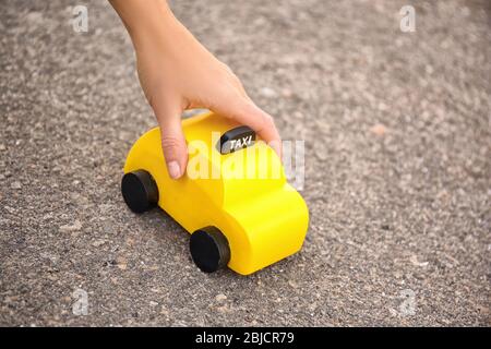 Frau hält gelbes Spielzeugtaxi auf dem Boden Stockfoto