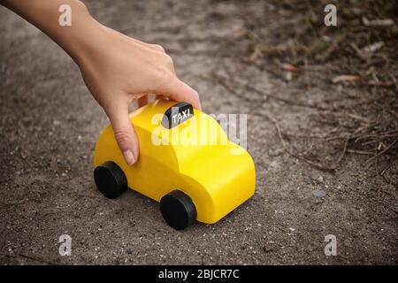 Frau hält gelbes Spielzeugtaxi auf dem Boden Stockfoto