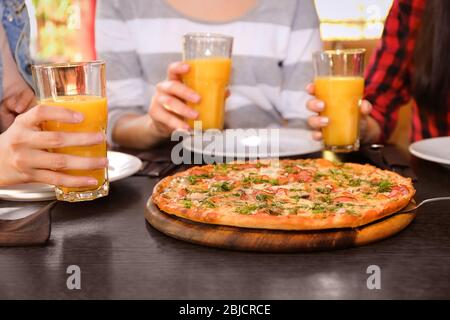 Freunde sitzen am Tisch mit Orangensaft und leckere Pizza, aus der Nähe Stockfoto