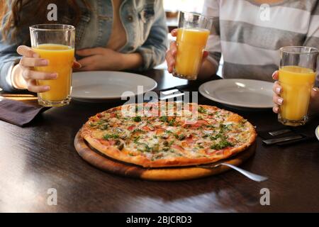 Freunde sitzen am Tisch mit Orangensaft und leckere Pizza, aus der Nähe Stockfoto