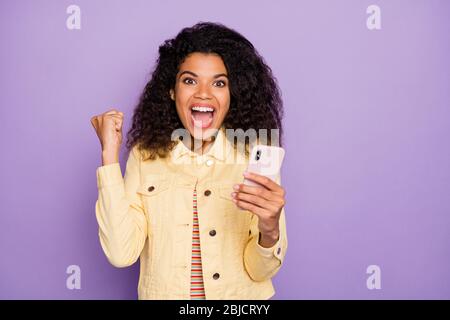 Foto von lockig gewellten braunen Haaren aufgeregt verrückte Frau fröhlich schreiend yeah modisch schreien in gelben Jacke isoliert Pastellfarbe Hintergrund Stockfoto