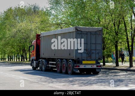 Nikolaev, Ukraine - 28. April 2020: Ein Getreidewagen mit einer Ladung Getreide auf einer Stadtstraße. Ein LKW mit grauem Anhänger fährt auf einer Stadtstraße zu einem Warehou Stockfoto