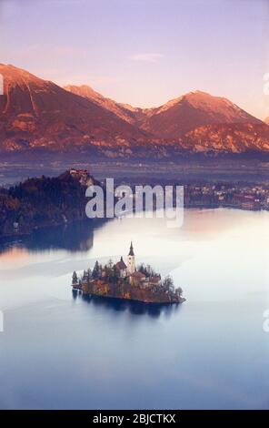 SEE BLED SLOWENIEN Blick auf den See die Insel und die Kirche auf einem perfekten Still Bled See bei rotem Sonnenuntergang mit Herbstfarbe Julische Alpen mit untergehenden Sonne hinter Slowenien Stockfoto