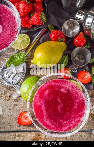 Sommer kalten Alkohol trinken. Erdbeer margarita Cocktail, mit Limette, Minze und frische Erdbeere auf rustikalem Holzhintergrund Stockfoto