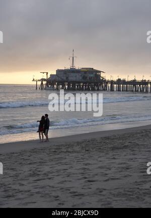 Santa Monica Pier am Abend, ein Paar am Strand, die letzten Sonnenstrahlen Stockfoto