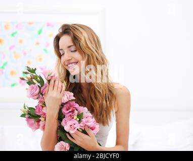 Junge glückliche Frau mit schönen Strauß von eustoma Blumen im Zimmer Stockfoto