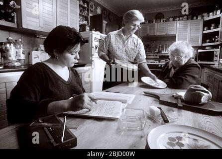 Familiengenerationen zusammen 1990er Jahre drei weibliche 3 Generationen zu Hause, die zusammen leben, mit älteren Großmutter, Mutter und Enkeltochter treffen sich zum Essen in ihrer Hausküche Stockfoto