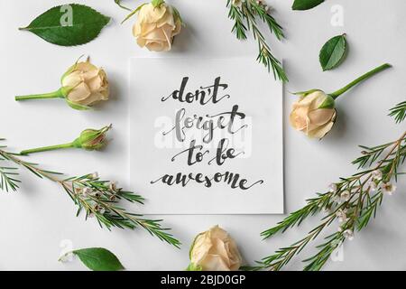 Zitat 'Don't forget to be awesome' auf Papier mit Rosen und Blättern auf weißem Hintergrund geschrieben. Draufsicht Stockfoto