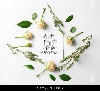 Zitat 'Don't forget to be awesome' auf Papier mit Rosen und Blättern auf weißem Hintergrund geschrieben. Draufsicht Stockfoto