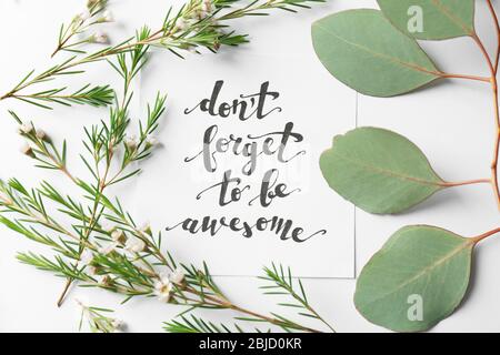 Zitat 'Don't forget to be awesome' auf Papier geschrieben mit Blättern und Blumen auf weißem Hintergrund. Draufsicht Stockfoto
